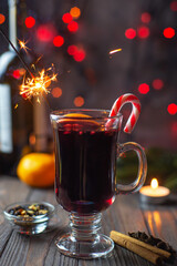 Mulled wine in a glass with sparklers and spices on a bokeh background
