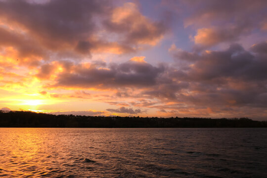 Dramatic sky over the water. Stormy landscape with dark clouds. View on a lake or sea at sunset or sunrise.