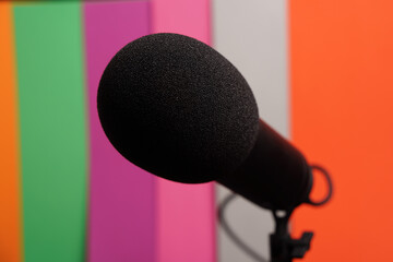 Microphone with black windproof pad on a multi-coloured background