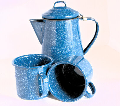 Closeup of camping coffeepot and two cups with a durable blue granite finish.
