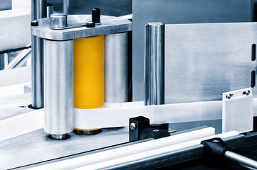 Fragment of the conveyor of sticking labeling machine. Abstract industrial background.