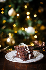 Chocolate brownies wrapped in group as a present in front of Christmas tree with Christmas lights in festive atmosphere and decoration