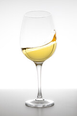 White wine swirling in glass on white background