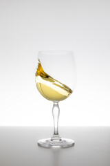 White wine swirling in glass on white background