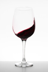 Red wine swirling in glass on white background
