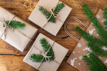 Gift bag, spruce branches and wrapped Christmas gifts in craft paper on wooden background