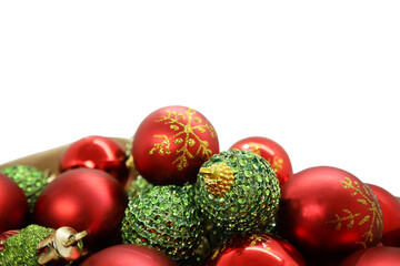 Red and green Christmas tree decorations in a box. Christmas balls isolated on white background with copy space.