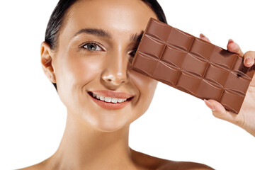 beautiful woman with makeup holding a chocolate bar on her face, isolated on white background. Spa...