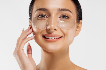 tender woman standing naked, with collagen blindfolds on her eyes, taking care of her skin with spots under the eyes
