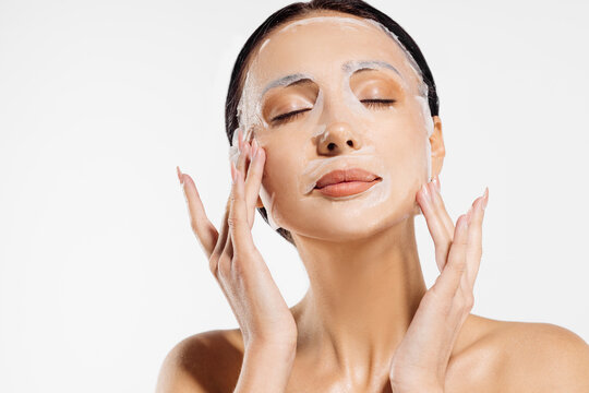 beautiful woman in a moisturizing facial mask, skin care. Woman applying a cosmetic tissue mask to her face