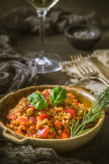 Homemade risotto made from spelt or rice with tomato and red bell pepper, wooden background, vertical