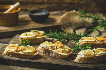 Baguette bread slices baked with goat cheese and honey, decorated with rosemary - obrazy, fototapety, plakaty