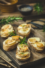 Baguette bread slices baked with goat cheese and honey on wooden background, vertical
