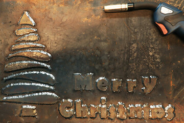 A steel sheet of metal on which a Christmas tree is welded and the phrase Merry Christmas....