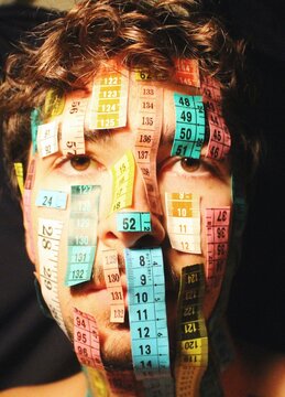 art portrait of young person with measuring tapes on face 