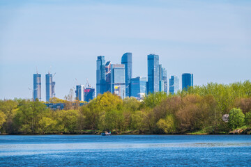 Fototapeta na wymiar River and green trees on background modern skyscrapers in the Moscow city. Panorama of new Moscow City buildings in spring