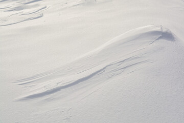 A beautiful snowy surface made of fluffy snow under a bright winter sun, with shadows on the snow. Merry Christmas and Happy New Year