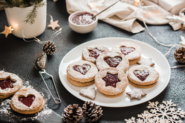 Ready Linzer cookies with berry jam on a plate on a dark background. Cooking Christmas treats. Lifestyle
