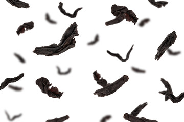 Falling black Tea leaves isolated on white background, selective focus