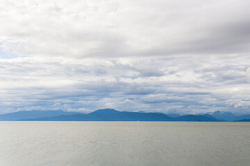 Fototapeta na wymiar view to the Strait of Georgia from Iona Beach Regional Park azure water cloudy blue sky