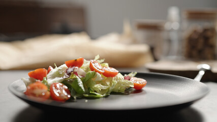 cherry tomatoes over mixed greens on black plate closeup