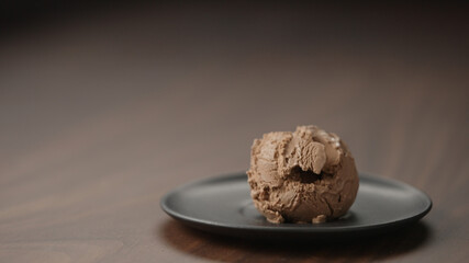 chocolate ice cream ball on small saucer on wood table