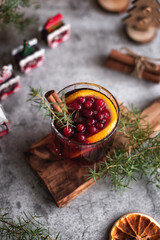 Christmas alcoholic beverages: cranberry punch in a glass with a slice of dried orange and a stick of cinnamon. Photo with lights. Photo of a drink in the Christmas decorations.