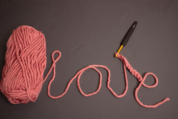 the word love made of pink threads of yarn and a skein of thread