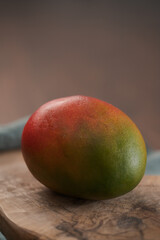 Whole ripe red mango on olive wood board