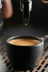 Closeup espresso last drop with single spout portafilter in black cup