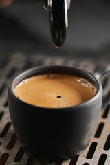 Closeup espresso last drop with single spout portafilter in black cup