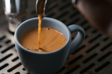 Closeup espresso pour with single spout portafilter in blue cup