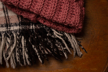 warm bright checkered scarf and knitted hat on a wooden background. cozy atmosphere