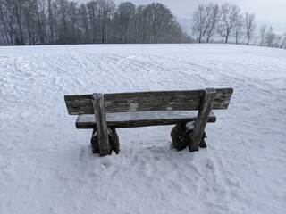 Eine Holzbank in einer Schneelandschaft auf dem Homberg am Hallwilersee in der Schweiz