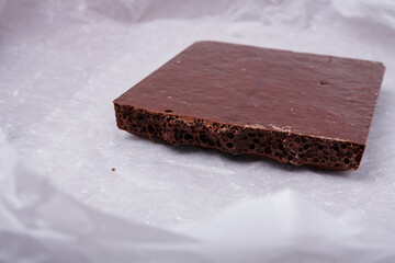 Porous chocolate bar on white paper. Bubbled or spongy chocolate, tasty sweets, carbohydrate food, sweet temptation, unhealthy diet
