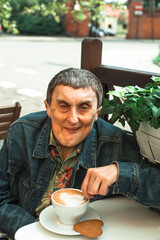 An disabled man suffering from cerebral palsy in the summer's street cafe.