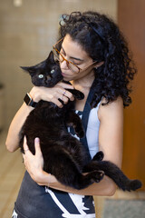 A brunette woman with curly hair petting her black male cat. Animal World. Animal life. Pet lover. Cat lover.