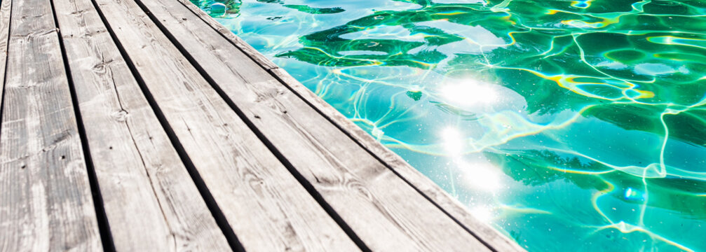 Sun glare on the water in an outdoor pool with a wooden board. Copy space