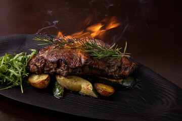 Grilled striploin steak on black dish. with fried potatoes and vegetables