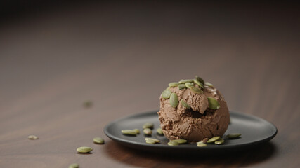 chocolate ice cream with pumpkin seeds on small saucer on wood table