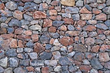 Textured background of masonry walls made of natural multicolored stones.