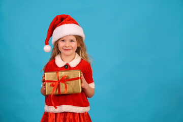 Happy merry Christmas child in Santa hat hold gift. beautiful girl smiles laughs. Congratulate celebration. Jolly Santa Claus preparing box gold red bow. Happy New Year. Place for text. Copy space. 
