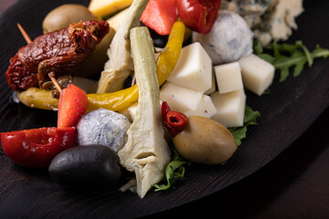 Palette of many types of cheese and some vegetables, tomatoes, paprika, olives.