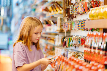 a funny little girl looks with interest at jewelry and souvenirs in the store. 