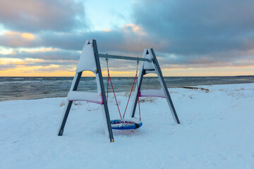 Swing in winter near the sea with a lot of snow