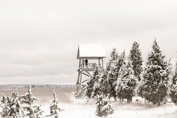 Wooden watchtower near from lake in cold and snowy winter