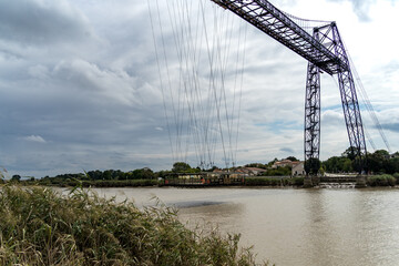 Transporter Bridge with nacelle over the Charente river under a cloudy sky. National monument. Rochefort sur mer. France