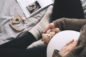 Woman pregnant belly with little teddy toy bear. Concept photo with symbol of many meanings for...
