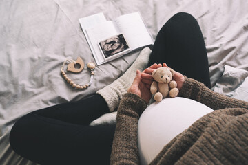 Woman pregnant belly with little teddy toy bear. Concept photo with symbol of many meanings for expectant mother during pregnancy and her unborn baby.