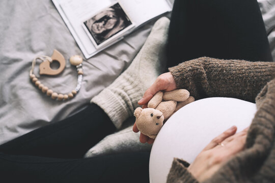 Woman pregnant belly with little teddy toy bear. Concept photo with symbol of many meanings for expectant mother during pregnancy and her unborn baby.